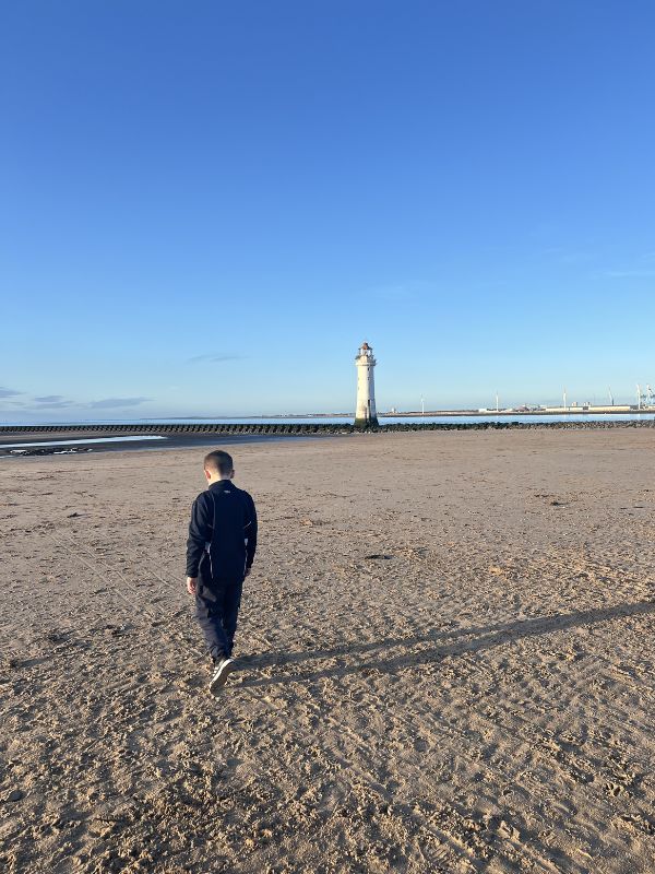 A child walking to the lighthouse in New Brighton. On the beach on a sunny day. A child walking to the lighthouse in New Brighton. On the beach on a sunny day.