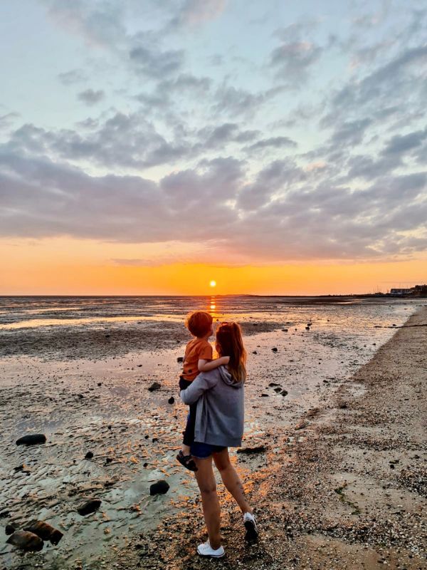 Mum and son watching the sun set in the distance at Caldy Beach in Wirral. Mum and son watching the sun set in the distance at Caldy Beach in Wirral.