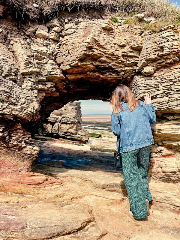 Girl looking through a cave in Hilbre Island.