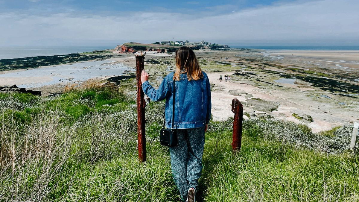 Girl looking out at the view of Hilbre Island in the distance.