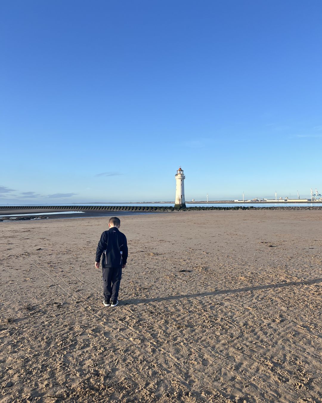 Young boy walking to New Brighton Lighthouse on a sunny day in Wirral. Young boy walking to New Brighton Lighthouse on a sunny day in Wirral.